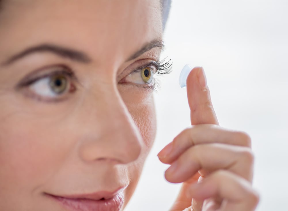 primer plano de una atractiva señora madura poniendose lentillas en sus ojos verdes